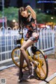 A woman in a short dress is sitting on a yellow bike.