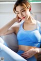 A woman in a blue sports bra sitting on a couch.