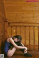 A woman in a blue leotard sitting on a wooden floor.