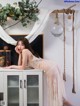 A woman in a white dress leaning on a cabinet.