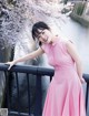 A woman in a pink dress leaning on a railing.