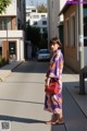 A woman in a purple kimono is standing on the street.