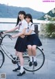 A couple of young women riding on the back of a bike.